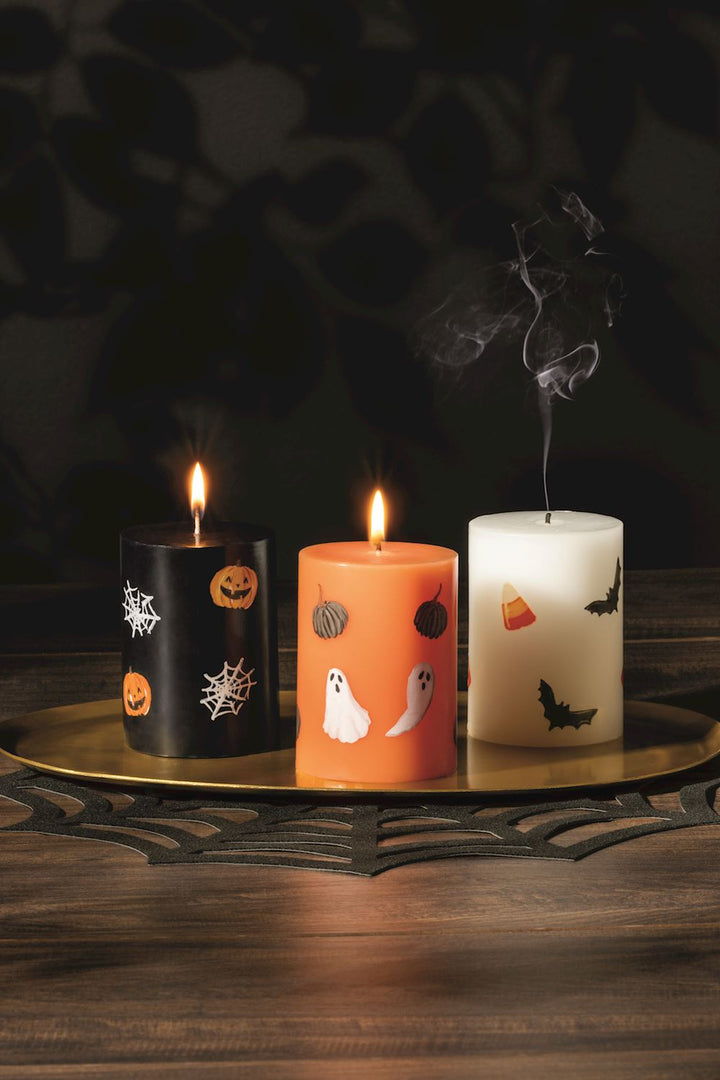 Three Halloween-themed candles on a dark background