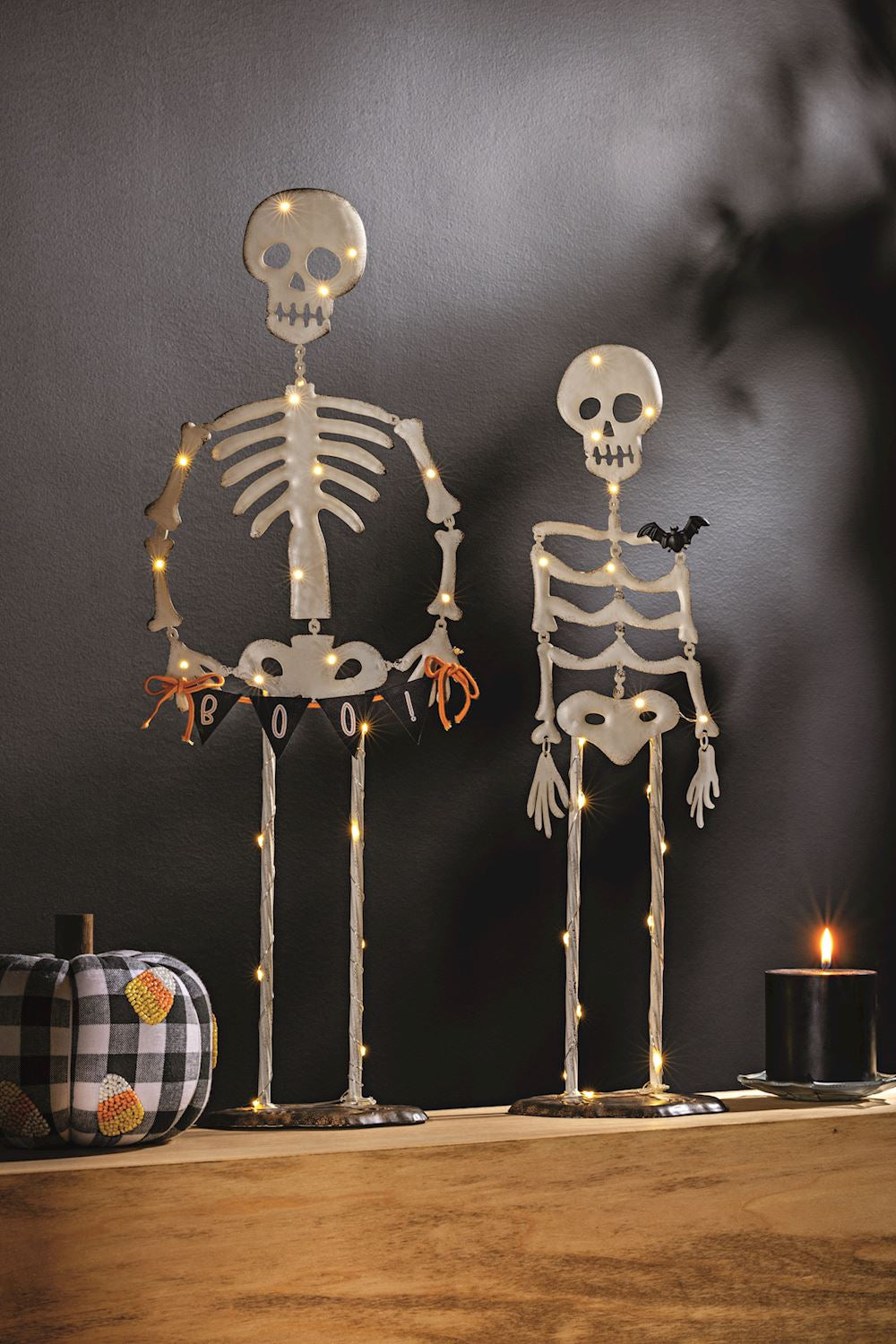 Two illuminated skeletons on a wooden surface with a dark background