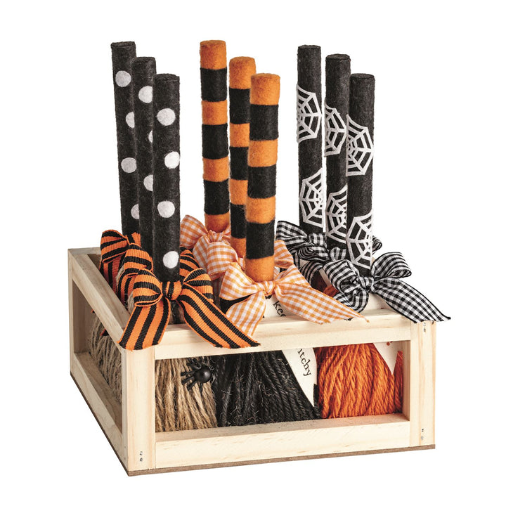 Decorative Halloween-themed sticks with bows in a wooden crate on a white background