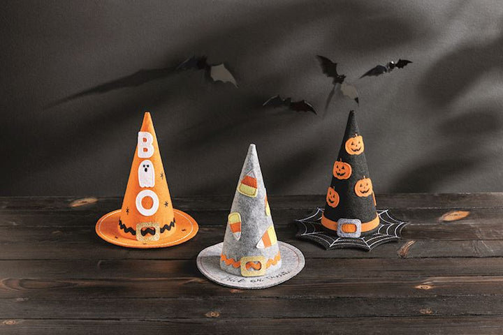 Three Halloween-themed decorative cones on a wooden surface with a dark background.