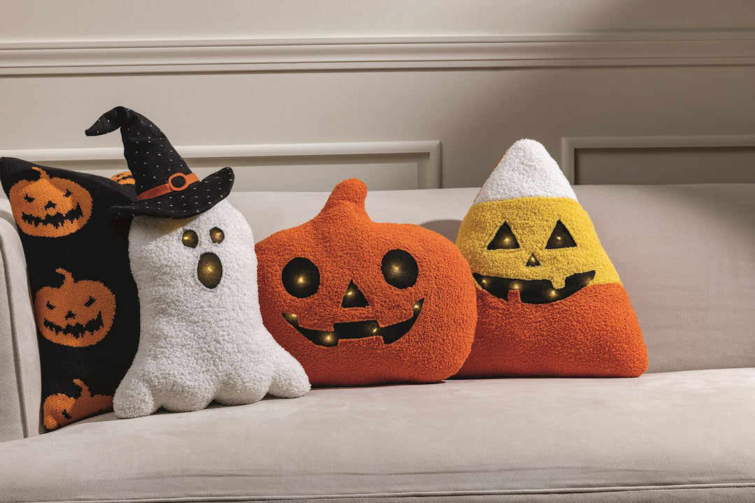Set of Halloween-themed decorative pillows on a couch.