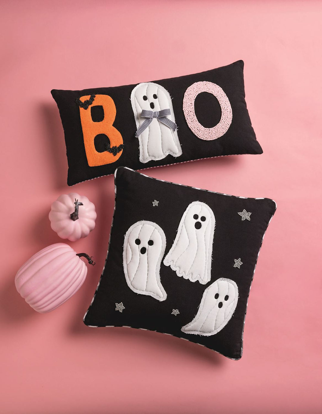 Halloween-themed decorative pillows with ghosts and 'BOO' text on a pink background