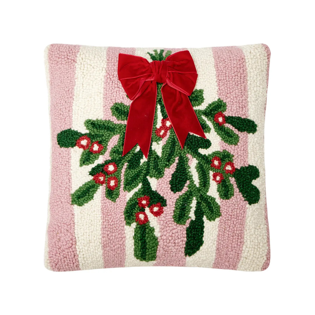 Decorative pillow with holly design and red bow on a pink and white striped background