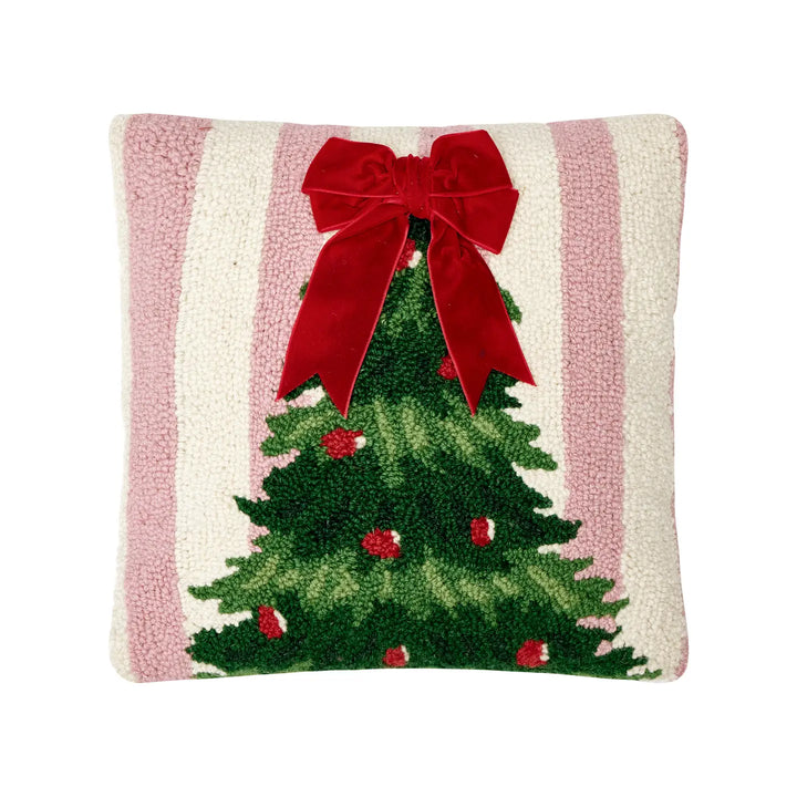 Decorative pillow with a Christmas tree and red bow design on a striped background.